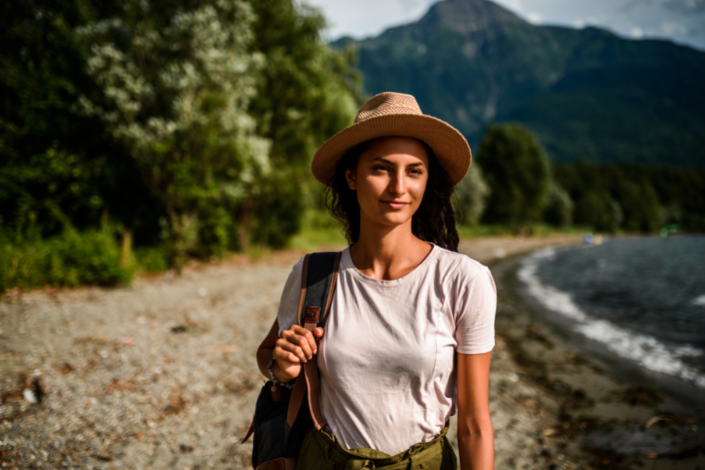 Femme avec un chapeau et un sac à dos qui se balade au bord d'un lac